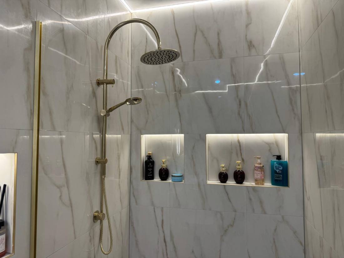 Detail of tiled shower niches and brass tapware