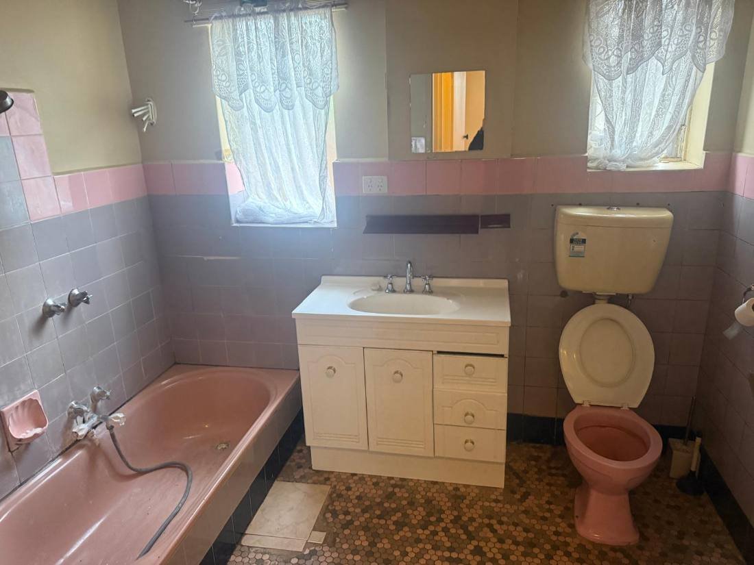 Dated bathroom before renovation, with original bath and vanity