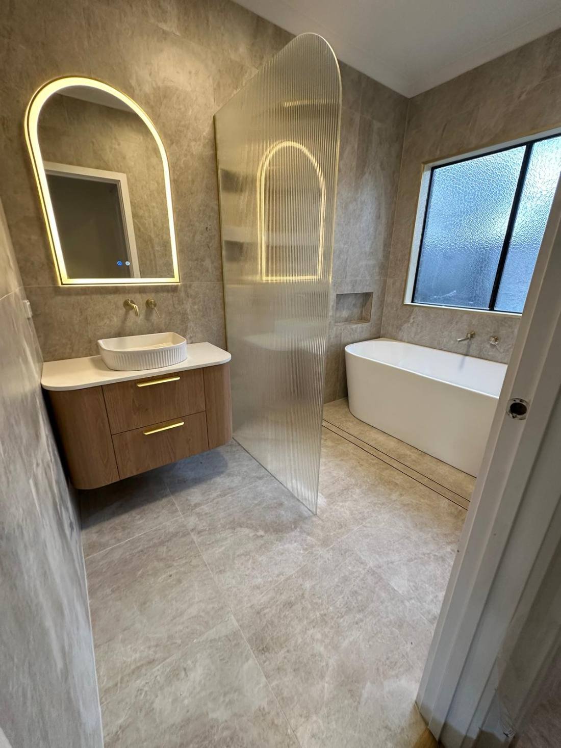 Completed bathroom renovation with freestanding bath and timber vanity